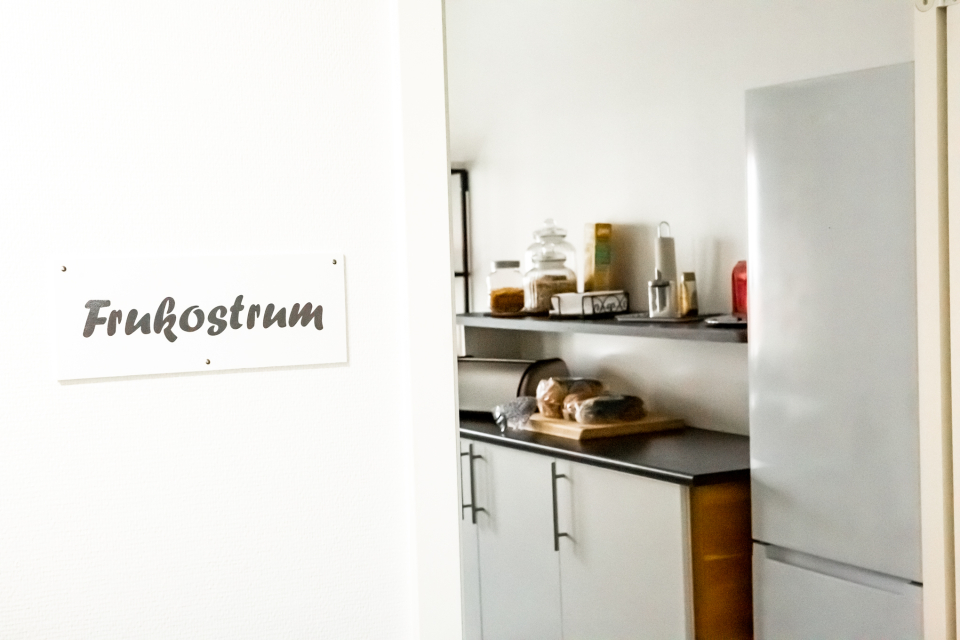En skylt med texten "Frukost" bredvid en dörröppning in till ett köp med bröd på diskbänken.